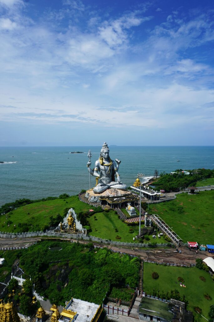 Majestic aerial view of the monumental Shiva statue in Murdeshwar, India against the vast ocean backdrop.