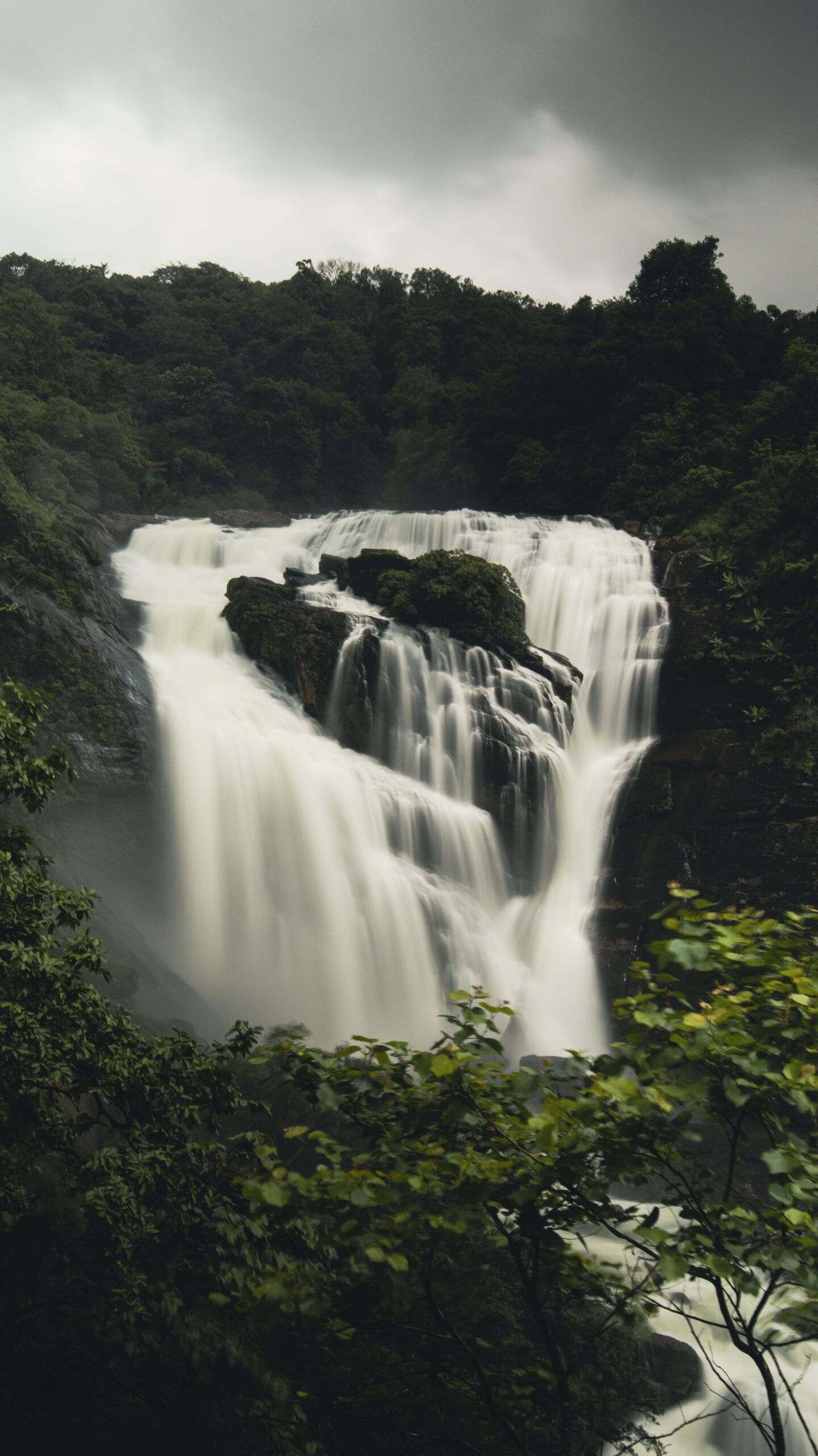 Stunning waterfall cascading amidst lush jungle landscape, creating a dramatic natural scene.