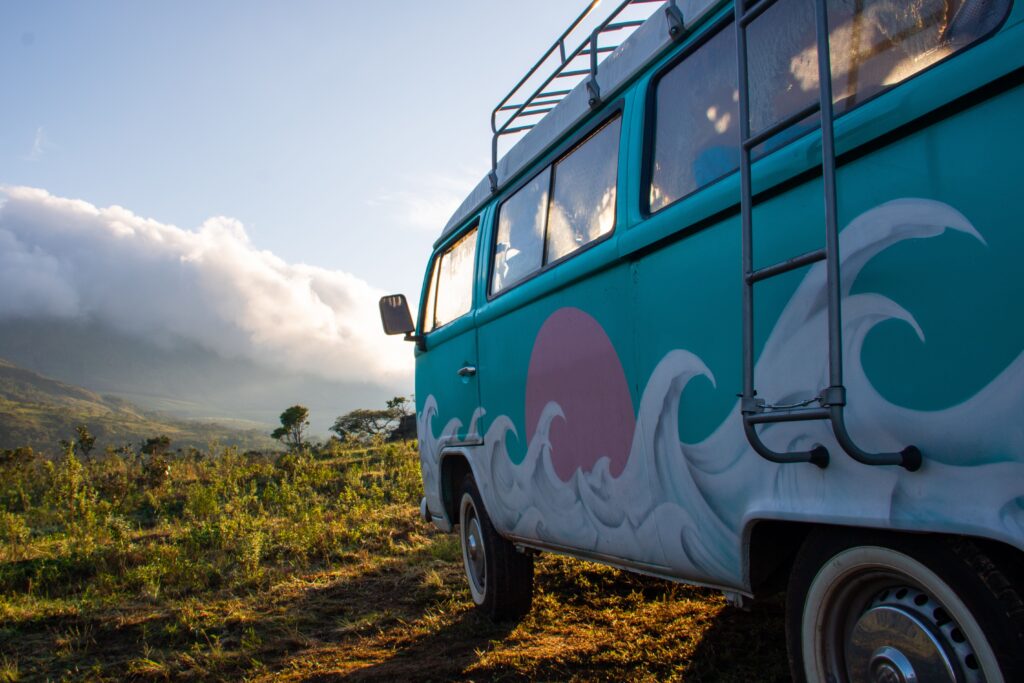 Colorful vintage camper van in a scenic outdoor landscape at sunrise.