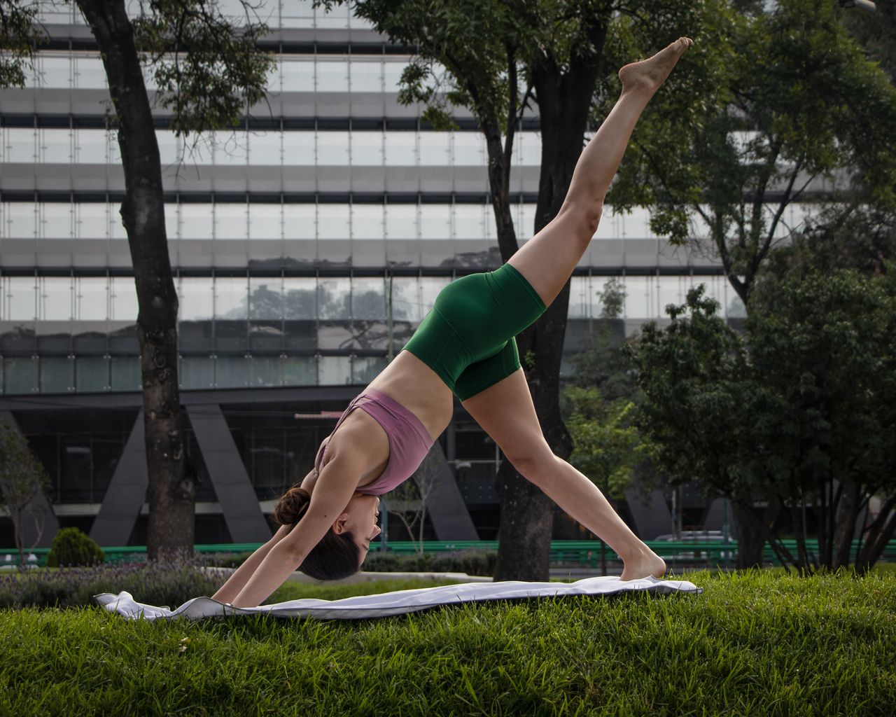 A woman practicing yoga in a park in Mexico City, showcasing balance and flexibility.