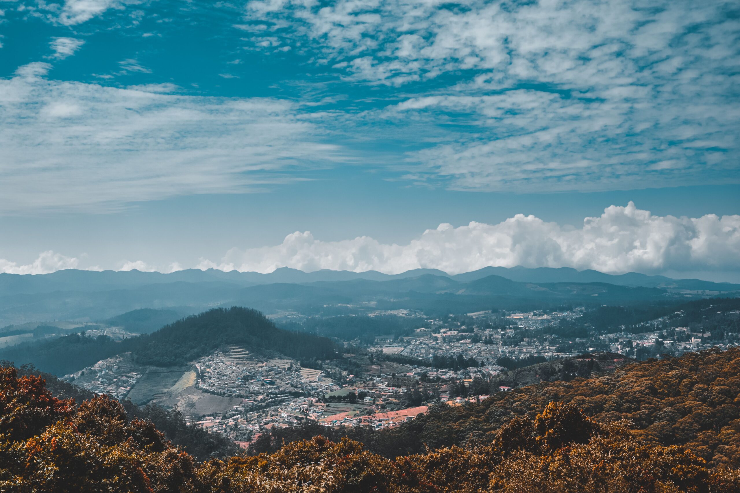 Breathtaking panoramic view of Ooty hills and town under a vibrant blue sky. Perfect for travel inspiration.